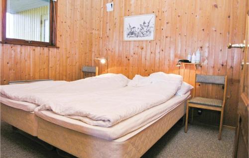 a bedroom with a large bed in a wooden wall at Awesome Home In Hvide Sande With Sauna in Havrvig