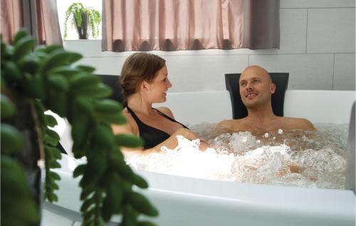 a man and a woman sitting in a bath tub at Nice Home In Tranekr With Sauna, Wifi And Indoor Swimming Pool in Hou