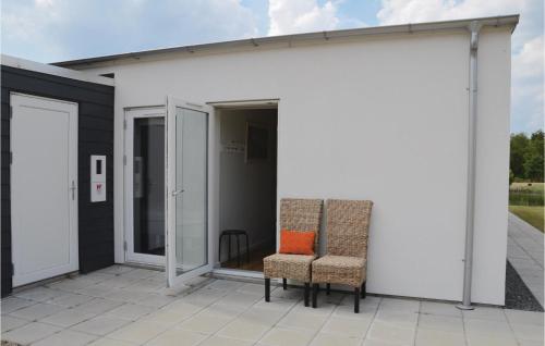 two chairs on the patio of a white building at Holiday Home Dyrefolden Ringkøbing Ii in Ringkøbing