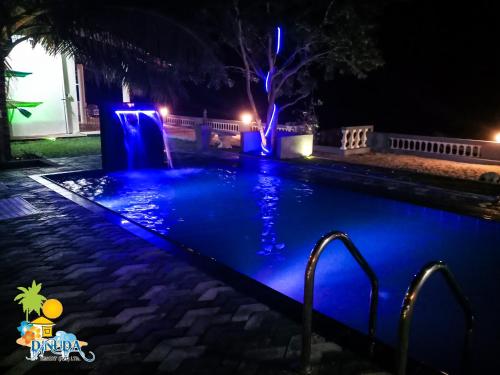 a swimming pool at night with blue lights at Dinuda Resort in Kalpitiya