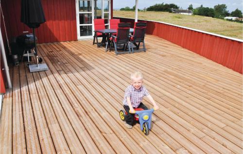 a young boy sitting on a deck playing with a toy car at Holiday Home Havmose Iii in Asserballeskov