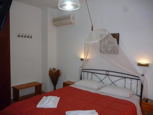 a bedroom with a bed with a red comforter at Kostas Apartments & studios in Agios Georgios Pagon