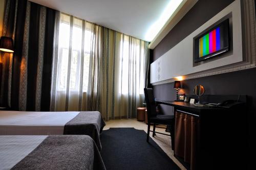 Habitación de hotel con cama, escritorio y TV. en City Art Boutique Hotel, en Ruse