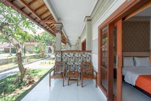 a bedroom with a bed and chairs on a balcony at Bendesa Accommodation in Kuta