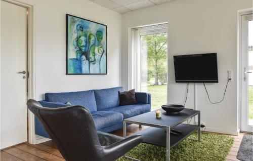 a living room with a blue couch and a tv at Holiday Home Dyrefolden Ringkøbing Vi in Hee