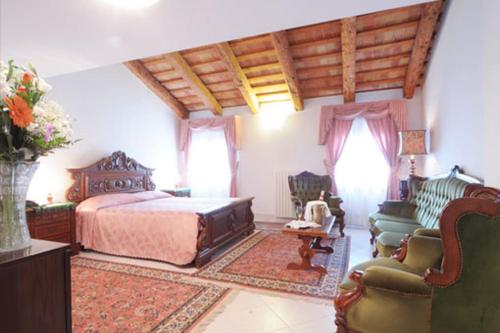 a bedroom with a bed and a couch and chairs at Stella d'Oro in Marano Lagunare