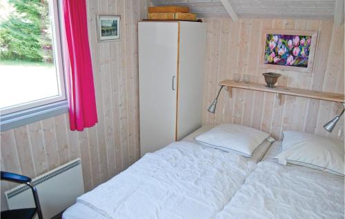 a small bedroom with a white bed and a refrigerator at Nice Home In Stege With 3 Bedrooms, Sauna And Wifi in Stege