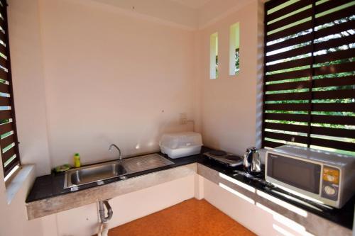 a kitchen with a sink and a microwave at Papai Country Lodge SHA in Ban Mae Pong