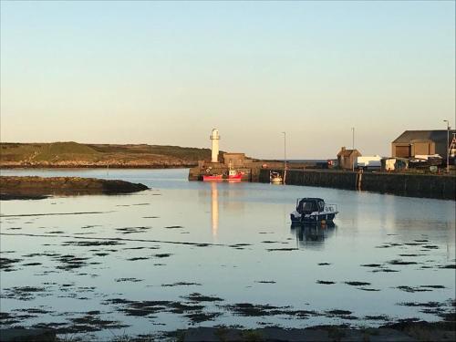 a small boat in a body of water with a lighthouse at Lovely apartment overlooking the harbour and bay in Ardglass