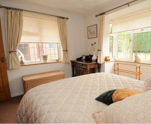 a bedroom with a large white bed and windows at Hopewell self-catering in Gravesend