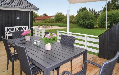 a black table with chairs and flowers on a deck at Holiday Home Solbærvangen V in Ovtrup