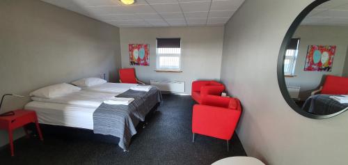 a bedroom with a bed and a mirror and red chairs at Vikingcafe in Höfn