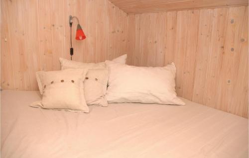 a bed with white pillows in a wooden room at Holiday Home Bøtøvej Væggerløse I in Marielyst