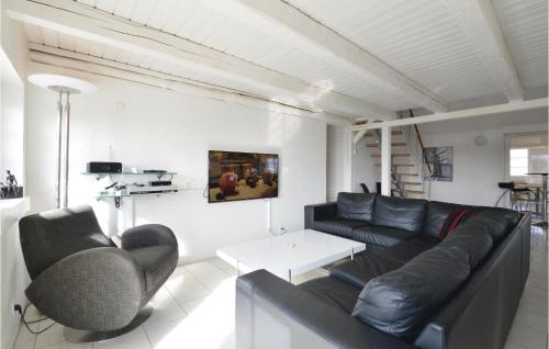 ein Wohnzimmer mit einer schwarzen Ledercouch und einem Tisch in der Unterkunft 6 Bedroom Awesome Home In Ringkøbing in Nørre Lyngvig