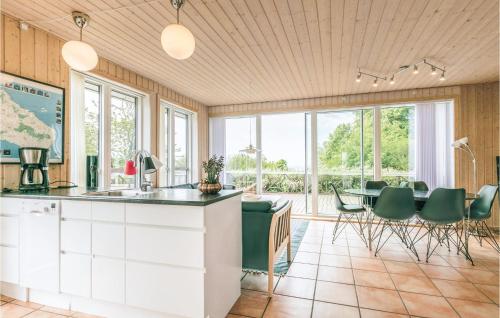 a kitchen with a table with green chairs and windows at Holiday Home Ved Brønden Hasle Xii in Hasle