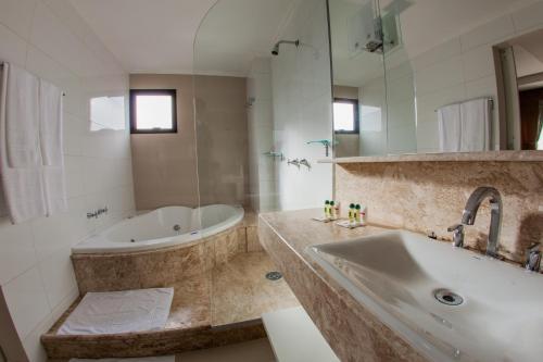 a bathroom with a bath tub and a sink at Santa Catarina Plaza Hotel in Canoinhas