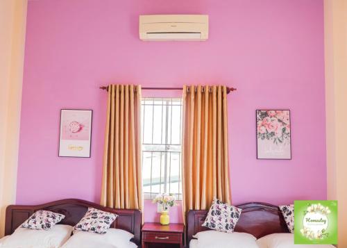 a purple room with two beds and a window at Can Tho Orchid Garden Homestay in Can Tho