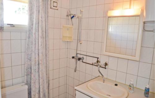 a white tiled bathroom with a sink and a mirror at 3 Bedroom Gorgeous Home In Vggerlse in Marielyst