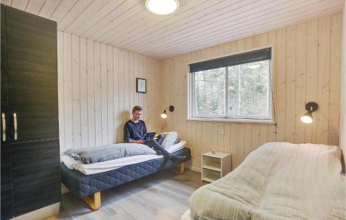 un uomo seduto su un letto in una camera da letto di Awesome Home In Frederiksvrk With Kitchen a Melby