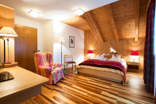 een hotelkamer met een bed en een stoel bij Ciasa Roby in San Cassiano