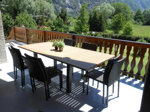 uma mesa de madeira e cadeiras num deque em Le Chalet Carpe Diem em Le Bourg-dʼOisans