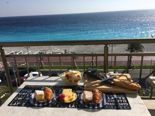 尼斯的住宿－LE MIRAGE, fantastic view，阳台上的餐桌和食物,享有海景
