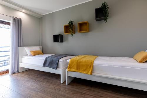 dwa łóżka w pokoju z białymi ścianami w obiekcie Amare Apartments A2 w mieście Mosty