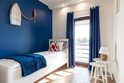 a blue bedroom with a white bed and a window at Amare Apartments B2 in Mosty