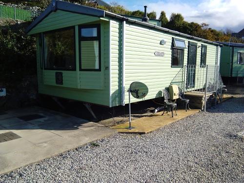a green trailer with a chair and a fan at Hendre Coed Isaf static caravan Barmouth in Barmouth