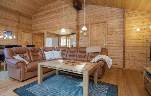 a living room with a brown leather couch and a table at Holiday Home Mads's Plantage Hadsund Xi in Helberskov