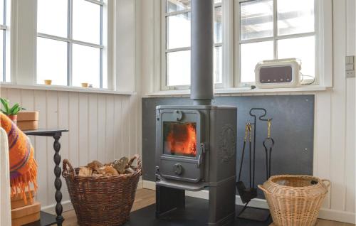 a wood stove in a living room with two windows at Three-Bedroom Holiday Home In Ulfborg in Fjand Gårde