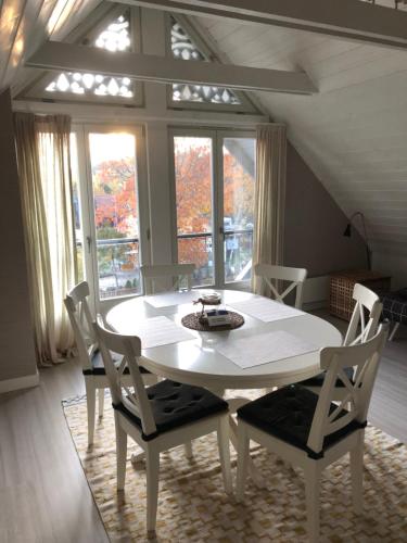 a white table and chairs in a room with windows at Marių pelėdos in Preila