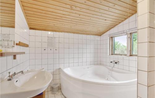 a white bathroom with a tub and a sink at Four-Bedroom Holiday Home In Tranekar in Tranekær