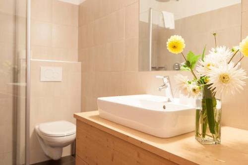a bathroom with a sink and flowers in a vase at Hotel Stefanshof in Plaus