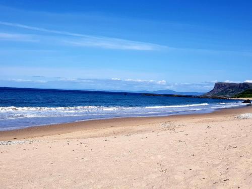 a sandy beach with the ocean in the background at Beach View Ballycastle Escape in Ballycastle
