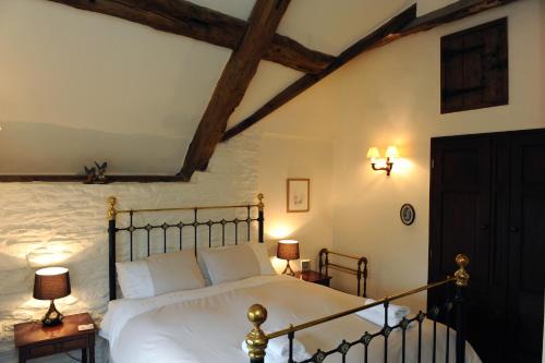 um quarto com uma cama grande e lençóis brancos em Steppes Farm Cottages em Monmouth