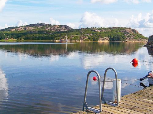 a dock with a boat on a lake with a mountain at 10 person holiday home in KLÖVEDAL in Klövedal