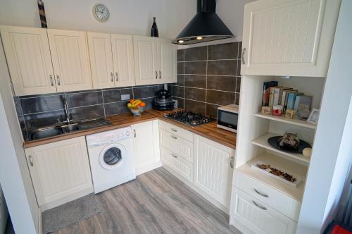 a kitchen with white cabinets and a washer and dryer at A Beautiful countryside apartment on killarney Road in Mallow