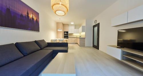 Residence Port Karolina في براغ: غرفة معيشة مع أريكة زرقاء ومطبخ