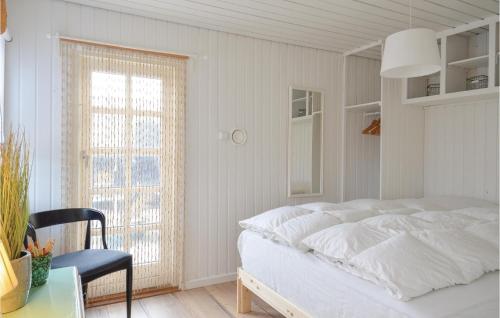 a bedroom with a bed and a chair and a window at Three-Bedroom Holiday Home In Ulfborg in Fjand Gårde