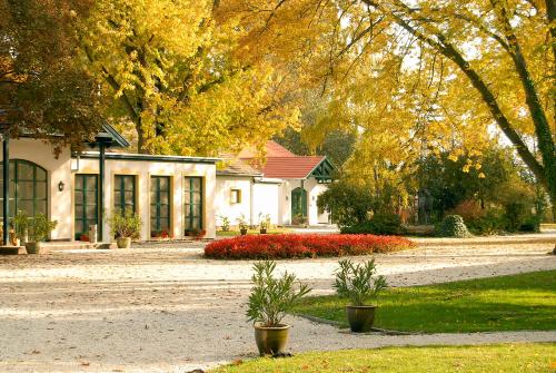 a white house with trees and flowers in front of it at Hubertus Hof Landhotel in Balatonfenyves