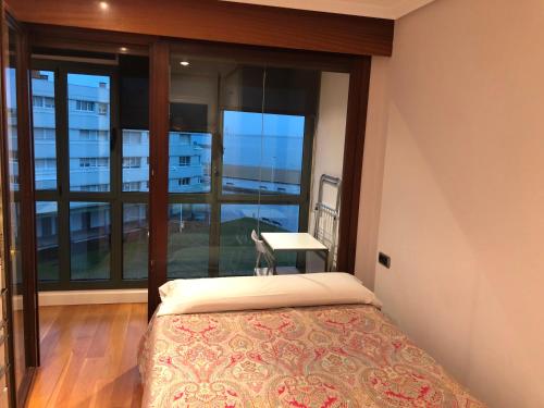 a bedroom with a bed and a window with a desk at PRIMERA LÍNEA PLAYA+PARKING GRATIS in Gijón