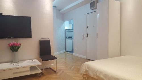 um quarto com uma cama e uma televisão na parede em Arena Relax Apartman em Belgrado