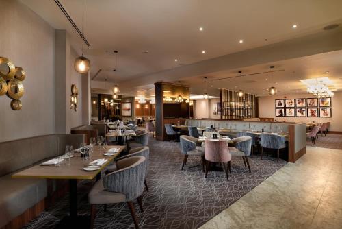 a restaurant with tables and chairs and a bar at Crowne Plaza London Heathrow T4, an IHG Hotel in Hillingdon