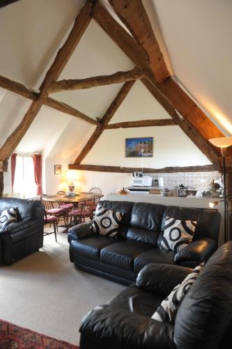 a living room with a black leather couch and a table at Steppes Farm Cottages in Monmouth