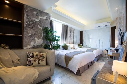 a hotel room with two beds and a couch at Hotel Maple Taiwan Boulevard in Taichung