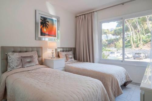 ミハスにあるMiraflores Apartmentのベッドが2つと大きな窓がある寝室