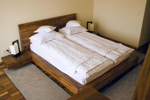 a large bed with white sheets and pillows at Anthimos in Baile Felix