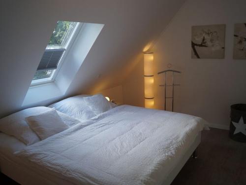 a bedroom with a white bed and a window at Zeitlos Langeoog in Langeoog