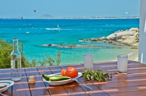 a table with a plate of vegetables and a view of the ocean at Ydreos Studios & Apartments in Mikri Vigla